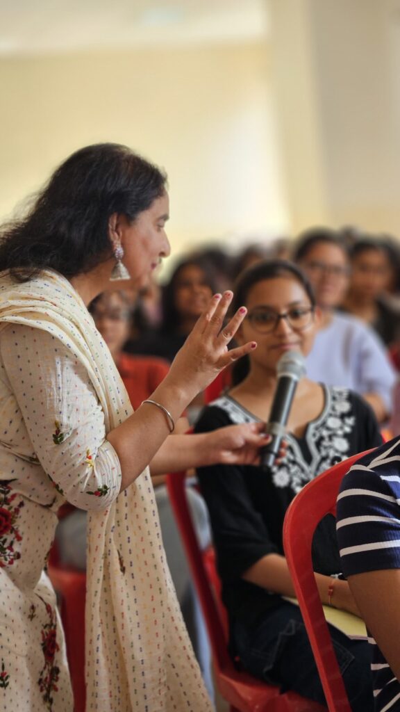 A woman speaks confidently to an engaged audience, sharing her ideas and insights.