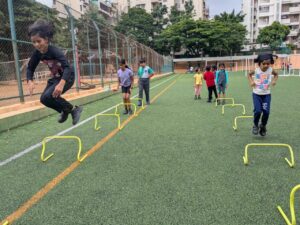 A lively scene of children engaged in a football game practice on a sunny field, demonstrating energy and camaraderie.